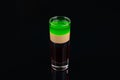 Green alcoholic shot glass with absent, irish cream, liquor on elegant dark black background