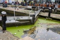 Green algae and lots of litter floating on the surface of the canal at one of the lock gates at Camden Lock