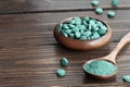 Green algae in powder and pills - chlorella, spirulina on a wooden background. Healthy green food supplement concept Royalty Free Stock Photo