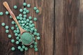 Green algae in powder and pills - chlorella, spirulina on a wooden background. Healthy green food supplement concept Royalty Free Stock Photo