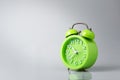 Green analog alarm clock gray background with light and shadow.