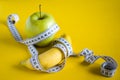 Green apple and banana with white tape measure on yellow background. Healthy lifestyle Royalty Free Stock Photo