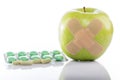 Green apple with a band-aid and varios pills Royalty Free Stock Photo