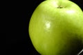 A green apple on a black background. Closeup. Royalty Free Stock Photo