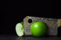 Green apple on a black background. kitchen hatchet chopping an apple in half.
