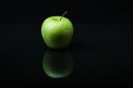 Green apple on a black background with reflection. Royalty Free Stock Photo