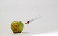 Syringe inserted into a green apple with an engraved skull, representative image of the use of gmo substances in food Royalty Free Stock Photo