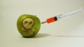 Syringe inserted into a green apple with an engraved skull, representative image of the use of gmo substances in food Royalty Free Stock Photo