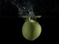 Green apple falls into the water, making a big splash Royalty Free Stock Photo