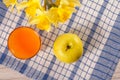 Green apple, glass of orange juice and bouquet of spring flowers on napkin Royalty Free Stock Photo