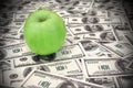 Green apple on heap of dollars