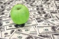 Green apple on heap of dollars