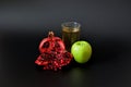 Green apple juice and pomegranate in a tall glass on a black background, next to pieces of ripe fruit Royalty Free Stock Photo