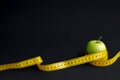 Green apple and measuring tape with centimeters and inches isolated on black background