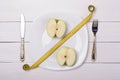 Green apple with measuring tape on a plate with knife and fork. Sale, percent. Royalty Free Stock Photo