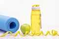 Green apple, measuring tape, water bottle and sports mats on a light wooden background Royalty Free Stock Photo