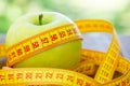 Green apple with measuring tape on wooden background. Apples and sewing tape measure on a wooden table. To lose weight and eat a Royalty Free Stock Photo