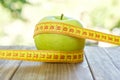 Green apple with measuring tape on wooden background. Apples and sewing tape measure on a wooden table. To lose weight and eat a Royalty Free Stock Photo