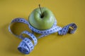 Green apple with measuring tape on yellow background Royalty Free Stock Photo