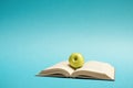 Green apple on an open book on blue background Royalty Free Stock Photo