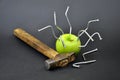 Green Apple pierced with nails. An old wooden hammer. Royalty Free Stock Photo