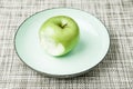 Green apple on plate, missing bite Royalty Free Stock Photo