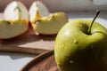 Green apple on a plate in the sun Royalty Free Stock Photo
