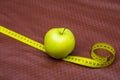 Green apple and ribbon on brown background. Measuring tape and apple. Fruits for weight loss. low calorie product. apple juice