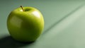 A green apple sits on a flat surface casting a shadow to the Royalty Free Stock Photo