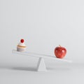 Green apple sitting on seesaw with cup cake on opposite end on white background