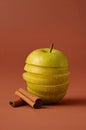 Green apple slices stack calmly beside cinnamon sticks on warm terracotta background Royalty Free Stock Photo