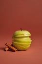 Green apple slices stack calmly beside cinnamon sticks on warm terracotta background Royalty Free Stock Photo