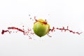 Green apple and splash of red juice on white background. Royalty Free Stock Photo