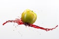 Green apple and splash of red juice on white background. Royalty Free Stock Photo