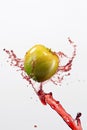 Green apple and splash of red juice on white background. Royalty Free Stock Photo