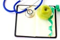 Green apple, stethoscope and measuring tap on notebook Royalty Free Stock Photo