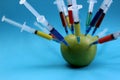 Green apple studded with a multi-colored syringe Royalty Free Stock Photo