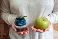 Green apple and sugar cupcake in the hands, the dilemma of what to choose, the concept of healthy eating and lifestyle