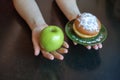 green apple and sugar donut in the hands, the dilemma of what to choose, the concept of healthy eating and lifestyle, the problem Royalty Free Stock Photo