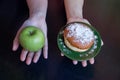 green apple and sugar donut in the hands, the dilemma of what to choose, the concept of healthy eating and lifestyle, the problem