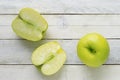 A green apple and two slices on a white wooden table Royalty Free Stock Photo