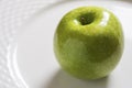 Green Apple on the White Plate. Shiny Organic Granny Smith Close Up. Royalty Free Stock Photo