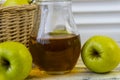 Green apples, basket with apples and jug with apple juice on wooden background Royalty Free Stock Photo