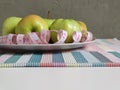 Green apples on a flat round plate with a measuring tape serpentine. white double-sided tape measure with inches and