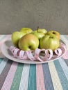 Green apples on a flat round plate with a measuring tape serpentine. white double-sided tape measure with inches and