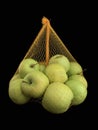 Green apples in a grid isolated on black. Ripe fruits in a string bag. Apple variety Royalty Free Stock Photo