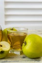 Green apples and jug with glass with apple juice on wooden background Royalty Free Stock Photo