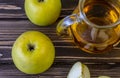 Green apples and jug with glass with apple juice on wooden background Royalty Free Stock Photo