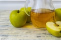 Green apples and jug with glass with apple juice on wooden background Royalty Free Stock Photo