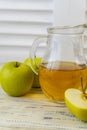 Green apples and jug with glass with apple juice on wooden background Royalty Free Stock Photo